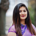 Close up portrait of indian hindu girl at traditional violet saree posed at street.